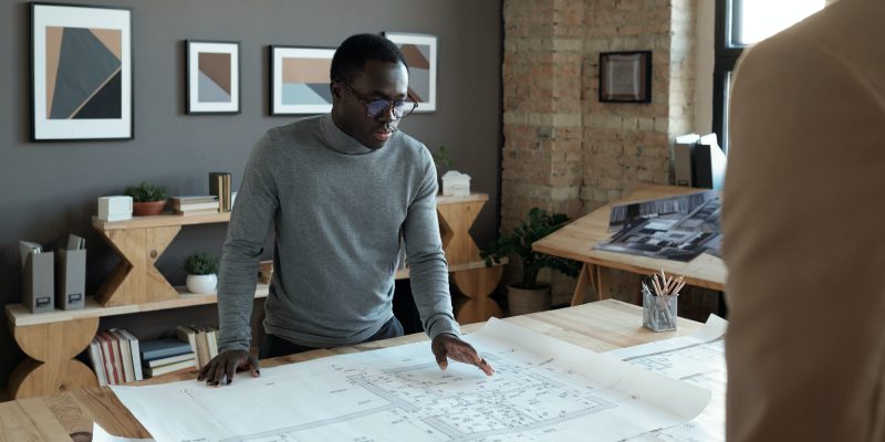 Young confident African engineer looking at sketch during discussion